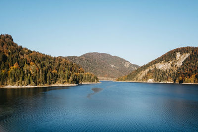 Scenic view of lake and mountains against clear blue sky