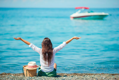 Rear view of woman with arms raised in sea