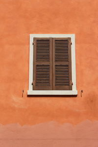 Low angle view of window on orange wall
