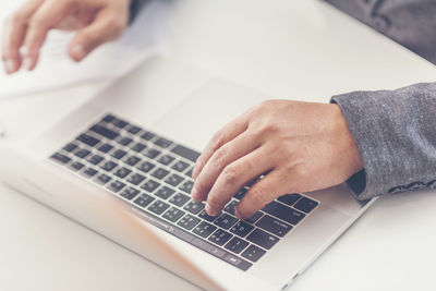 Midsection of person using laptop on table