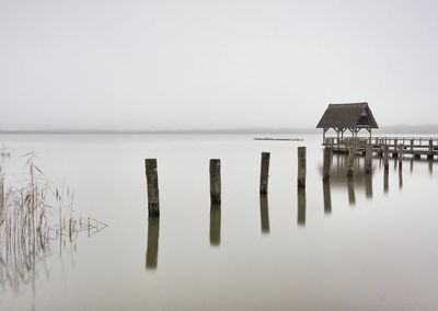 Wooden posts in lake against sky