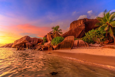 Rock formations by sea against sky during sunset