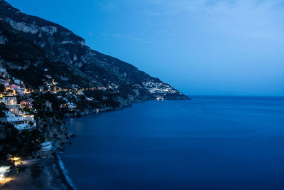 Scenic view of sea and mountains against blue sky