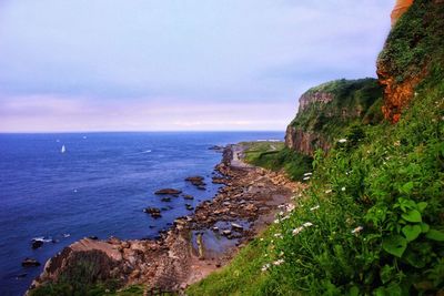 Scenic view of sea by cliff against sky