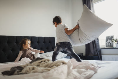 Rear view of friends relaxing on bed at home