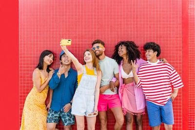 Cheerful friends standing against wall