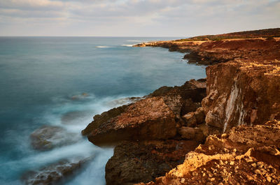 Scenic view of sea by cliff against sky