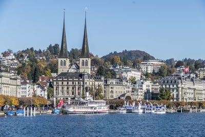 Sailboats by buildings in city against clear sky