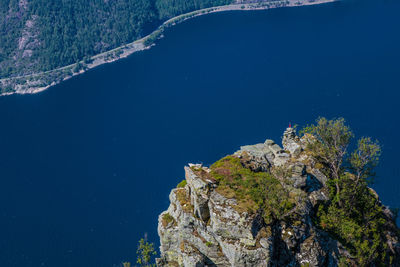 High angle view of rocks by sea against blue sky