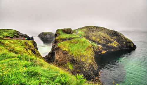 Scenic view of rocks by sea against sky