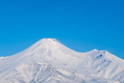 Scenic view of snowcapped volcano against clear blue sky