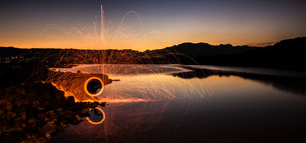 Person light painting by lake at sunset
