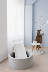 The interior of the children's room is decorated in blue and beige colors. the bear holds