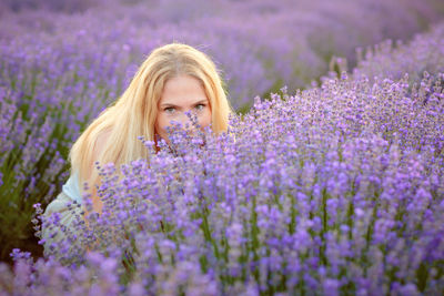 Portrait of young woman standing amidst purple flowers