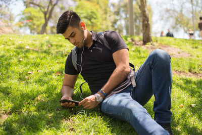 Young man listening music on phone at park