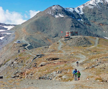 Rear view of people walking on mountain against sky