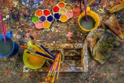 Directly above shot of paintbrushes and watercolor paints on table