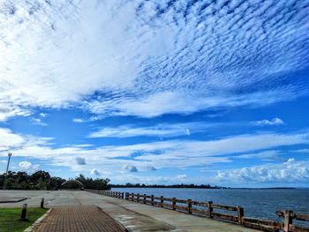 Empty road by sea against blue sky