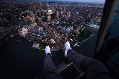 Low section of man sitting in helicopter over buildings in city