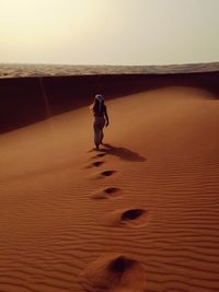 Full length of man standing on shore against sky during sunset