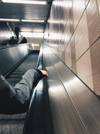 Cropped hand on escalator railing at subway station