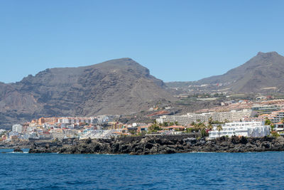 Scenic view of sea by buildings against clear sky