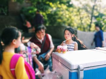 Girl with ice creams standing by container at park
