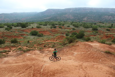 Rear view of cyclist standing on field