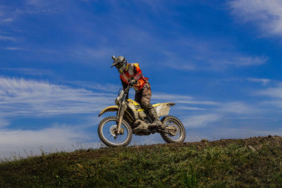 Low angle view of man riding bicycle on field against sky