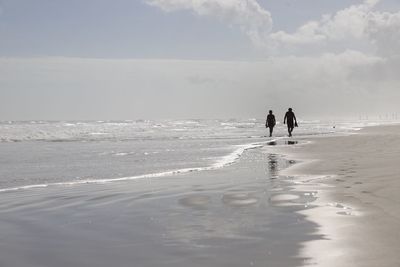 Silhouette of couple walking along deserted beach