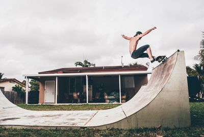 Low angle view of young woman jumping against built structure