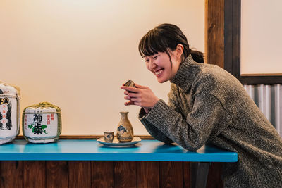 Young woman using phone while sitting on table