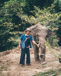 Full length of man standing by elephant against trees at forest