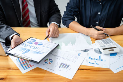 Midsection of business colleagues working on table