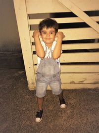 Portrait of cute boy standing against wooden door