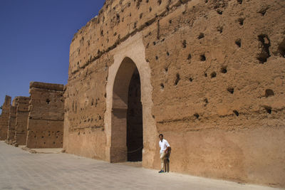Rear view of woman standing at historical building against sky