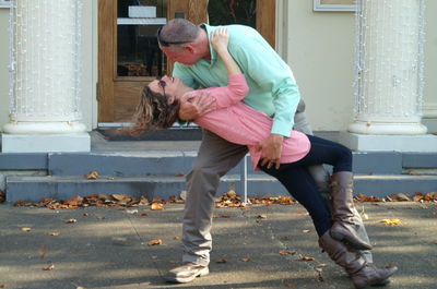 Full length of mature couple posing against building