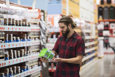 Male customer reading label on nail box in hardware store