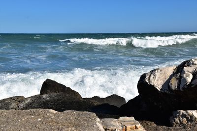 Scenic view of rocks in sea against clear sky