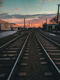 Surface level of railroad tracks against sky at sunset