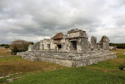 Old ruin building in field against cloudy sky