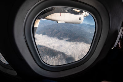 Reflection of clouds in sky seen through airplane window