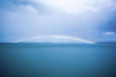 Scenic view of rainbow over sea against sky