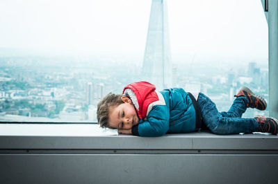 Portrait of boy lying on glass window