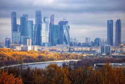 Modern buildings in city against sky during autumn