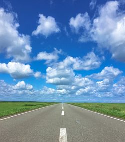 Empty road amidst field against sky