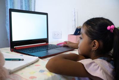 Portrait of girl using laptop on table