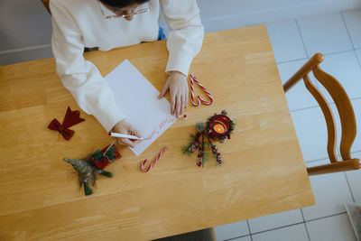 A teenage girl writes a letter to santa claus at the table.