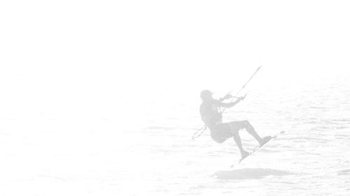 Man holding umbrella in sea against clear sky