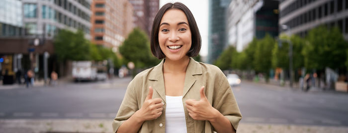 Portrait of young woman standing in city